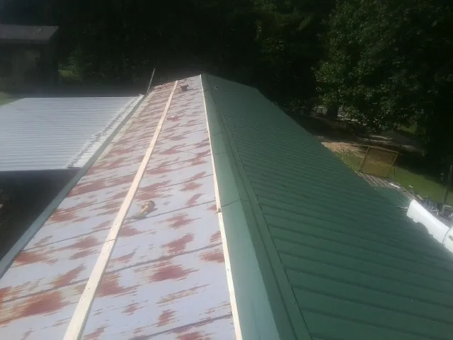 Old rusted panels beside newly installed green metal roofing — Wind Damage Roof Repair by Roofing Brothers in Glen Mills