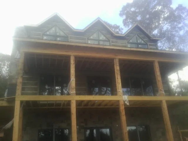 Dormers and porch framing on a large log home under construction — Roof Coating work by our crew in Glen Mills
