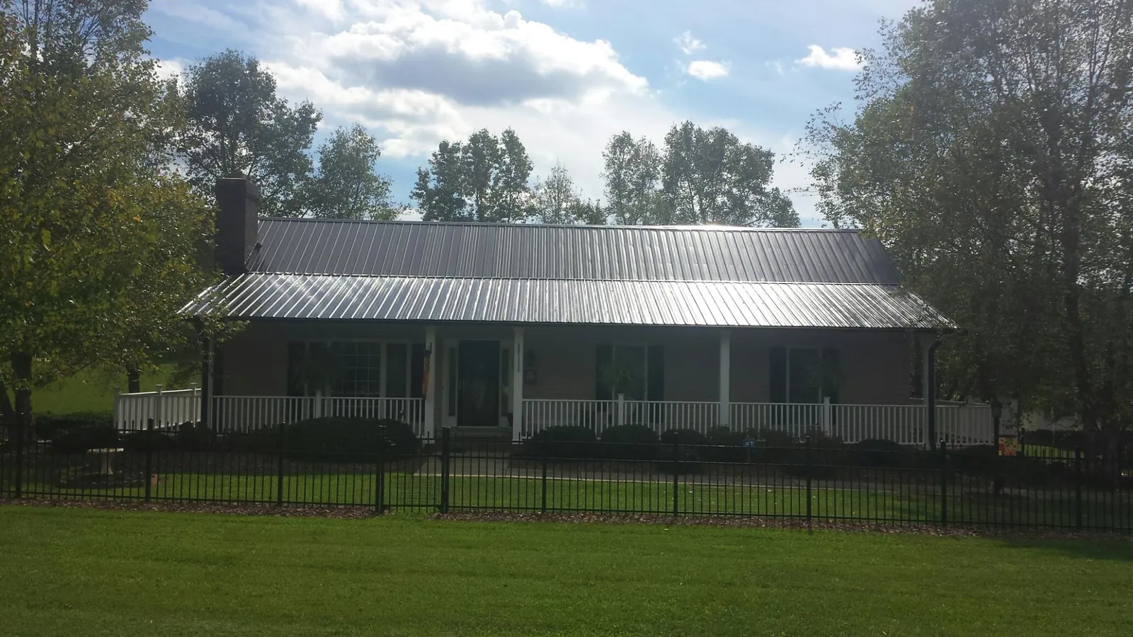 Gray metal roof on a brick ranch with a full width front porch — Gutter Guard Installation work by our crew in Glen Mills