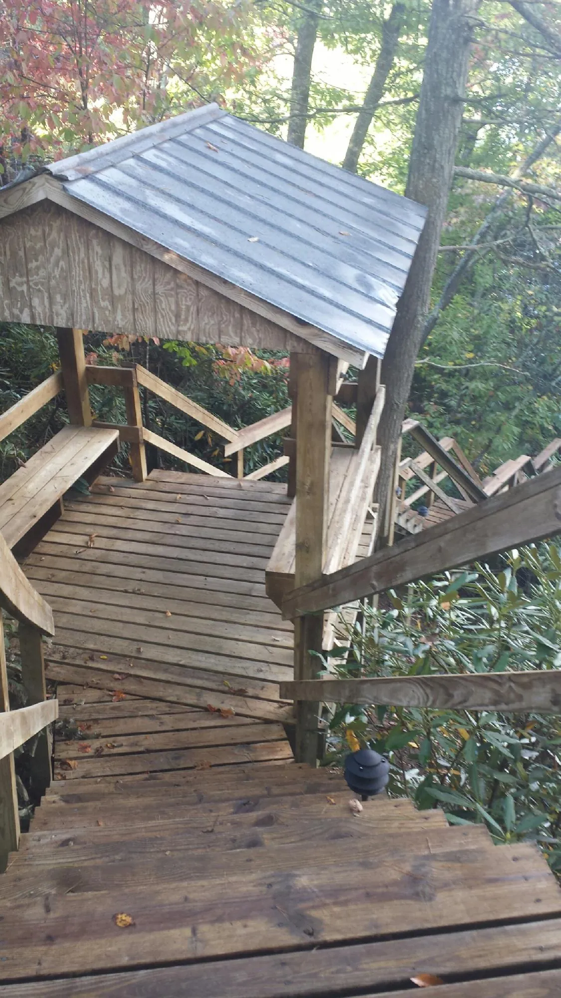 Metal roofed shelter over wooden steps on a wooded walkway — Skylight Repair & Installation work by our crew in Glen Mills