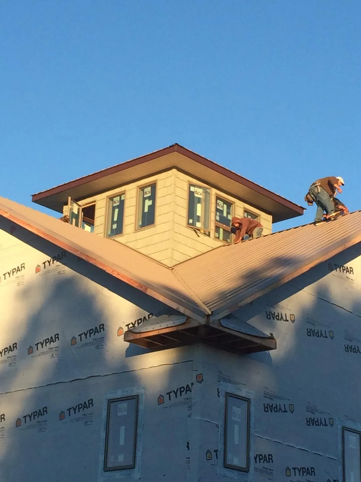 Roofers working around a rooftop cupola on a new metal roof at sunset — Roof Waterproofing in Glen Mills by Roofing Brothers